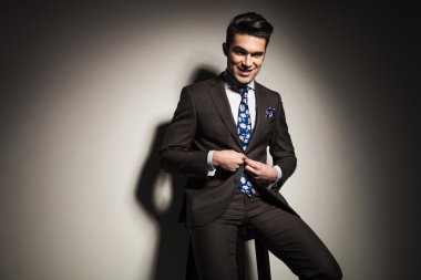 Ceketini kapatılması sırasında bir taburede oturan iş adamı