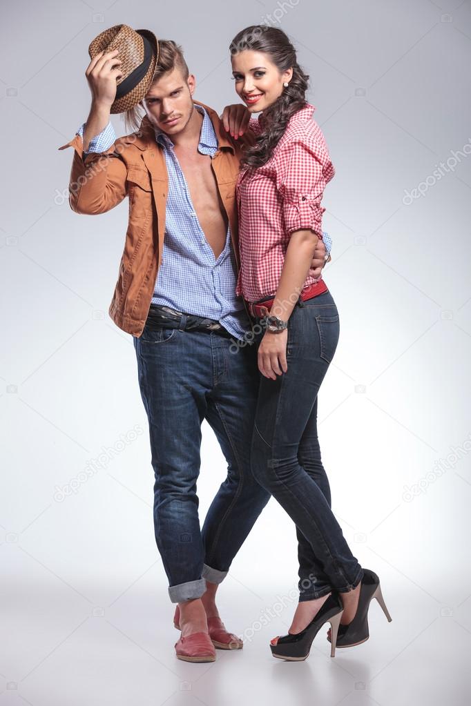 man taking off his hat while his girlfriend is smiling