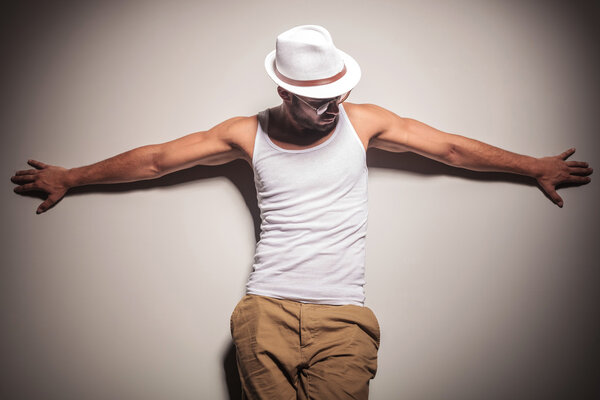 Sexy young casual man leaning on a white wall