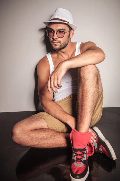 Casual young man sitting on while looking away — Stock Photo, Image