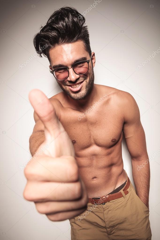 shirtless young man showing the thumbs up gesture 