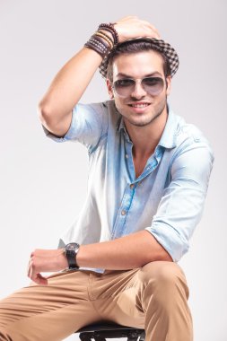 Gülümseyen moda adam bir taburede rahatlatıcı