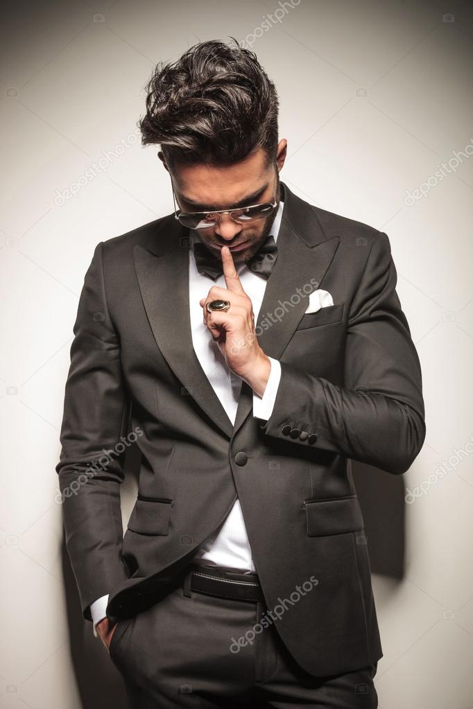 business man holding one finger to his mouth