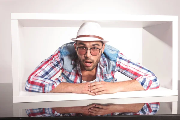 Amazed young fashion man lying inside a white box. — Stock Photo, Image