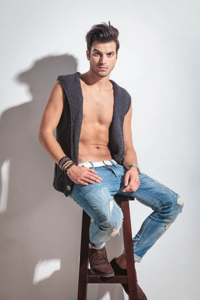 Sexy young casual man sitting on a wood stool — Stock Photo, Image