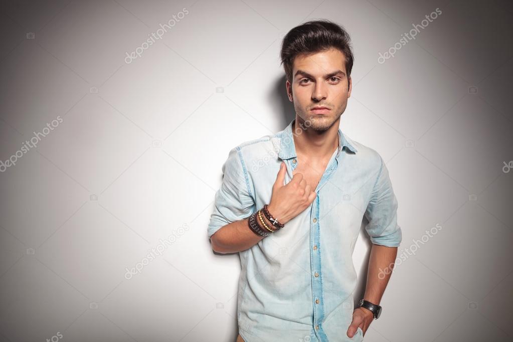 Cool young fashion man leaning on studio background