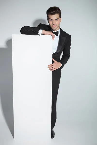 Homem de negócios elegante apoiando-se em um quadro branco — Fotografia de Stock