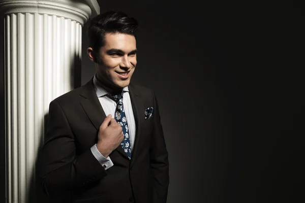 Smiling young business man fixing his suit — Stock Photo, Image