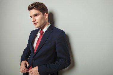  Ceketini kapatılması sırasında bir duvara yaslanmış iş adamı