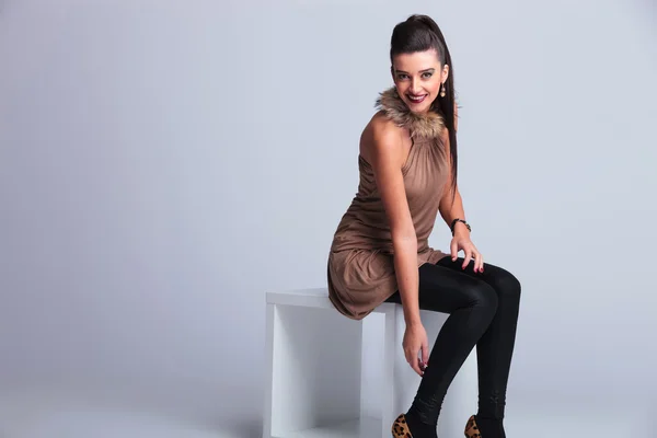 Happy young fashion woman sitting on a white chair — Stock Photo, Image