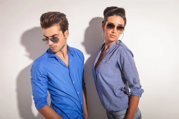 Man and woman posing against a grey wall — Stock Photo, Image