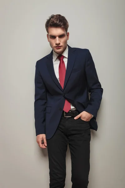 Stilig ung affärsman lutande på en grå vägg — Stockfoto
