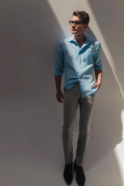 Jovem homem de moda apoiando-se em uma parede cinza — Fotografia de Stock