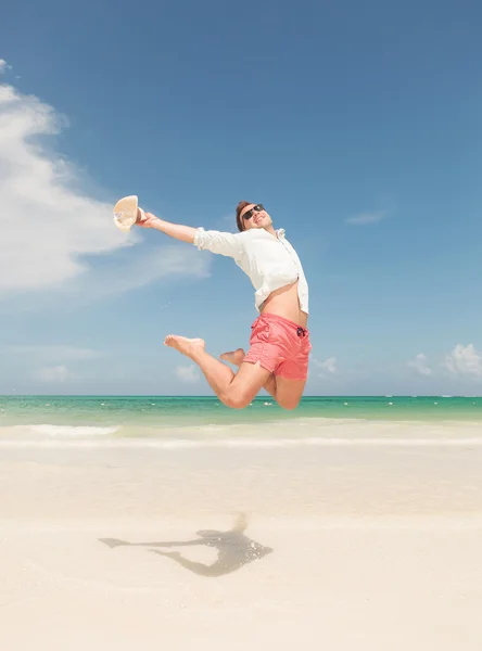 Glücklicher junger Mann springt auf den Strand — Stockfoto