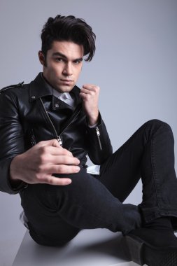 Bacaklarını çapraz oturan genç moda adam 