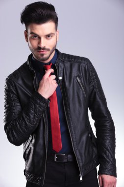 Kravatını tamir ederken kameraya gülümseyen iş adamı.