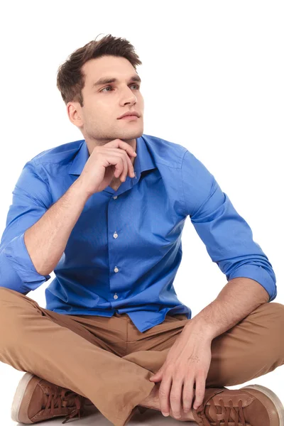 Nachdenklicher junger Mann sitzt mit gekreuzten Beinen — Stockfoto