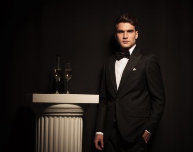 Siyah bir duvara yaslanmış zarif genç iş adamı 