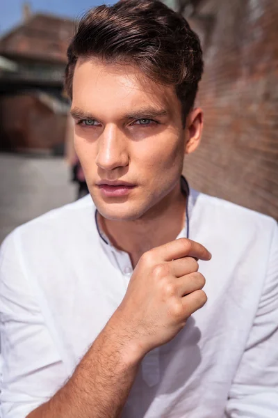 Jovem homem de moda posando perto de uma parede de tijolo . — Fotografia de Stock