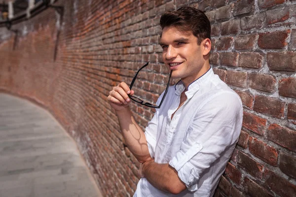 Sonriente joven de la moda sosteniendo sus gafas en su mano . —  Fotos de Stock