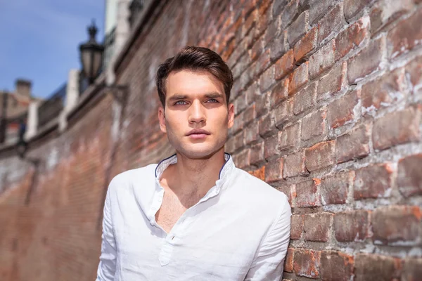 Hombre guapo de la moda apoyado en una pared de ladrillo —  Fotos de Stock