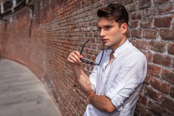 Pensive young fashion man holding his glasses — Stock Photo, Image
