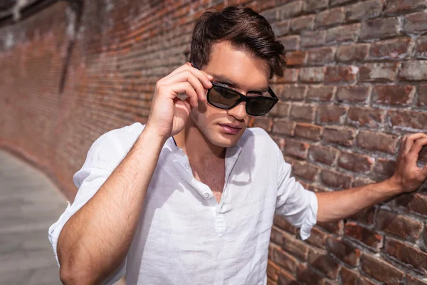 Beau jeune homme enlevant ses lunettes de soleil . — Photo