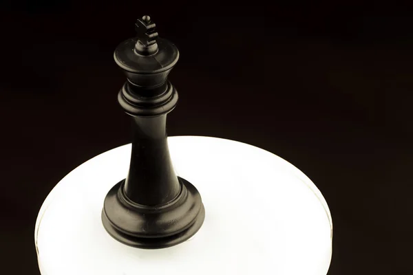 Μαύρο βασιλιά του σκακιού σε ένα λευκό λαμπερό κύκλος — Φωτογραφία Αρχείου