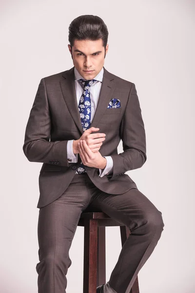 Business man sitting on a stool holding his hands together. — Stock Photo, Image