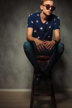 bir taburede oturan bir genç moda adam görüntüsünü kesip 