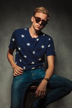 güneş gözlüğü ile sandalye üzerinde oturan moda adam