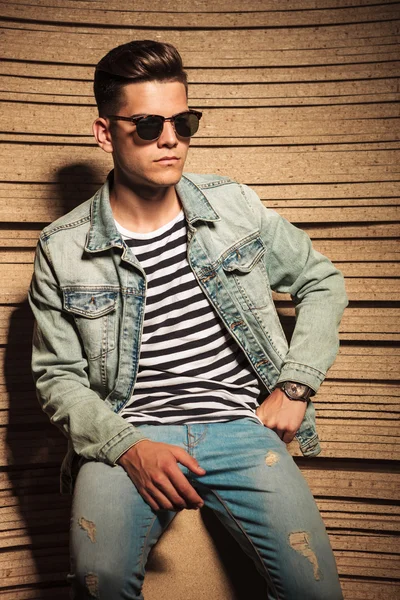 Onhartelijk mens in jeans jasje en zonnebril zit — Stockfoto