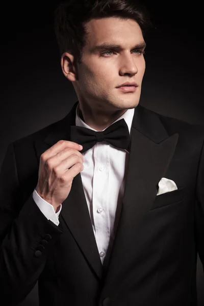 Handsome young elegant man fixing his bowtie. — Stock Photo, Image