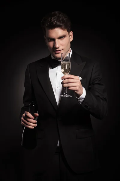 Elegant man holding a bottle and a glass of champagne. — Stock Photo, Image