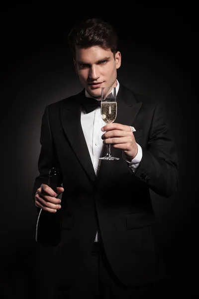 Hombre elegante sosteniendo una botella y una copa de champán . — Foto de Stock