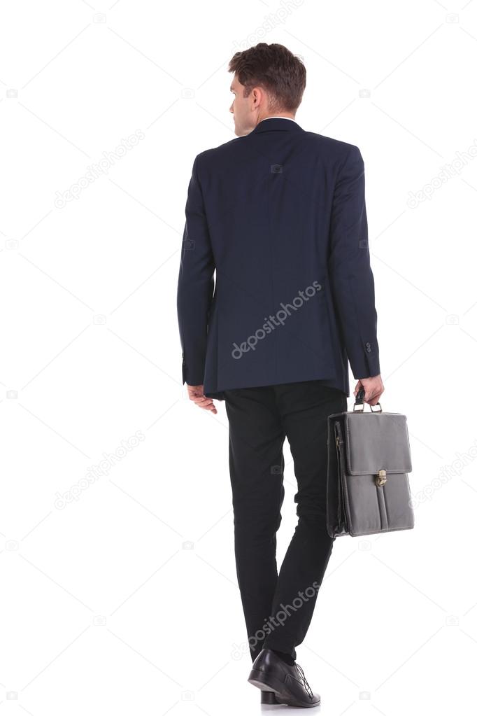 business man walking while holding his briefcase.