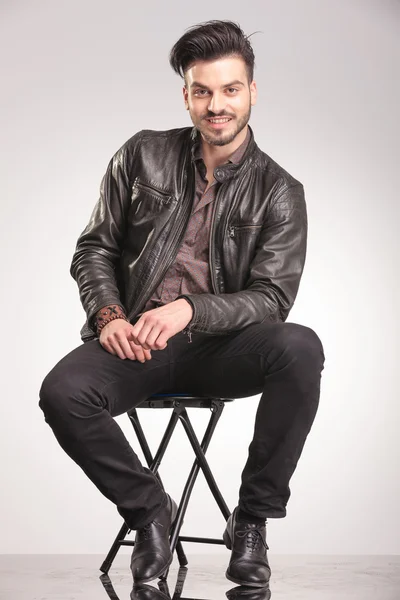 Smiling young fashion man sitting on a chair — Stock Photo, Image