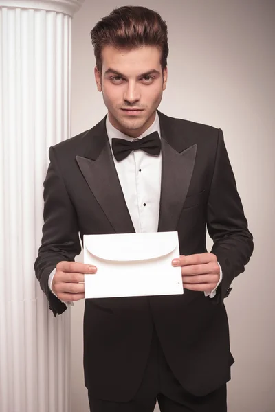 Handsome young business man giving you a white envelope. — Stock Photo, Image