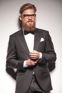 Happy young business man fixing his button.