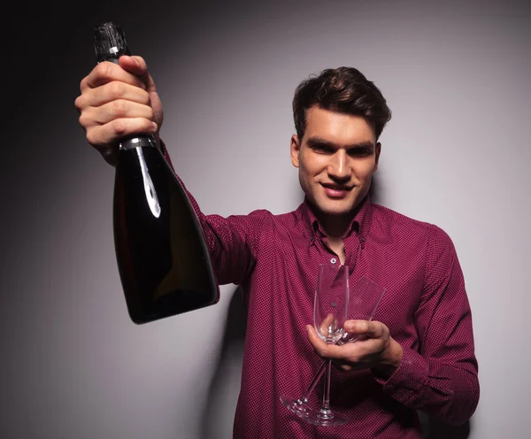 Casual young man presenting a bottle of wine — Stock fotografie