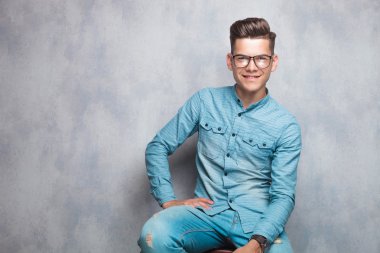 Happy young fashion man sitting