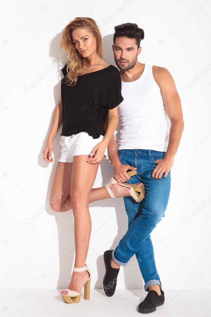 Cute young couple leaning on a white wall 