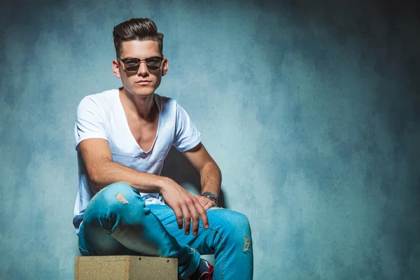 Casual young man sitting on a wood box — ストック写真