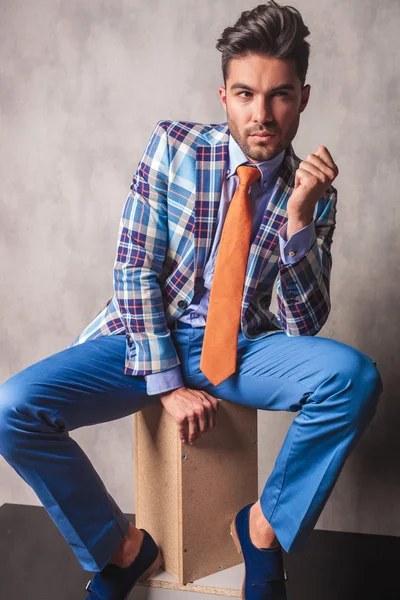 Attraktiver junger Geschäftsmann sitzt auf einer Holzkiste. — Stockfoto