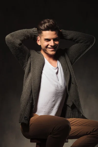 Smiling young man sitting on a chair — Stock Photo, Image