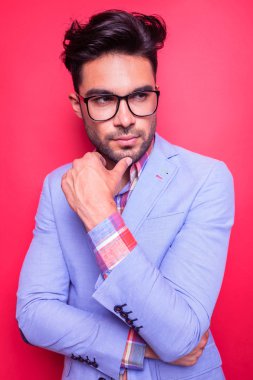 Pensive young man holding his thumb to the chin