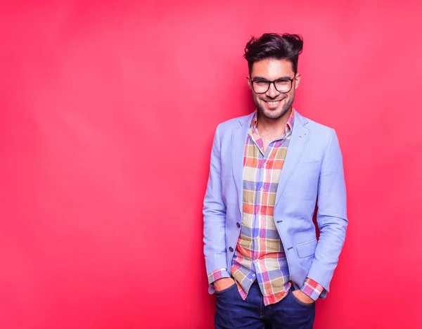 Sorrindo jovem homem de moda segurando as mãos nos bolsos — Fotografia de Stock