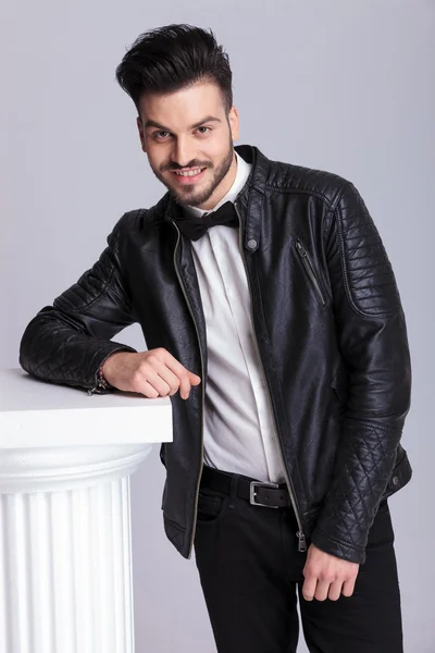 Happy young business man leaning in a white column. — Stock Photo, Image