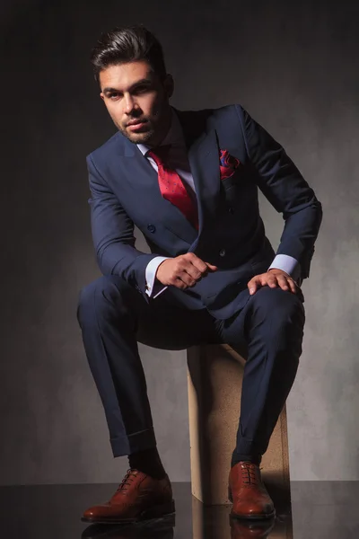 Elegant business man sitting on a wood box while thinking. — Stock Photo, Image