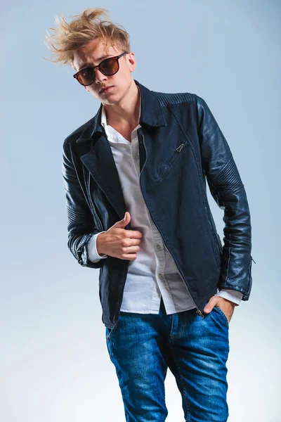 Sexy man posing while holding his leather jacket with sunglasses — Stock Photo, Image